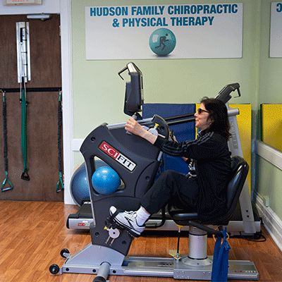 Female patient on an exercise bike receiving physical therapy at Hudson Family Chiropractic